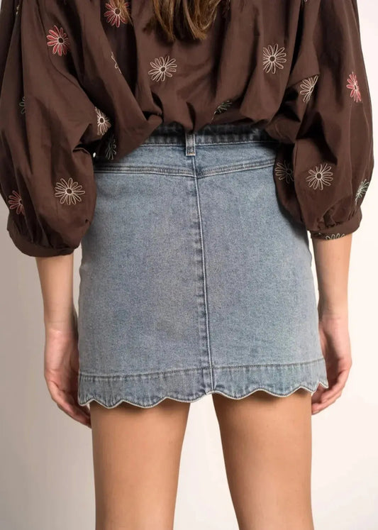 Jupe en jean courte femme, taille haute, bas festonné, blouse marron à fleurs brodées.