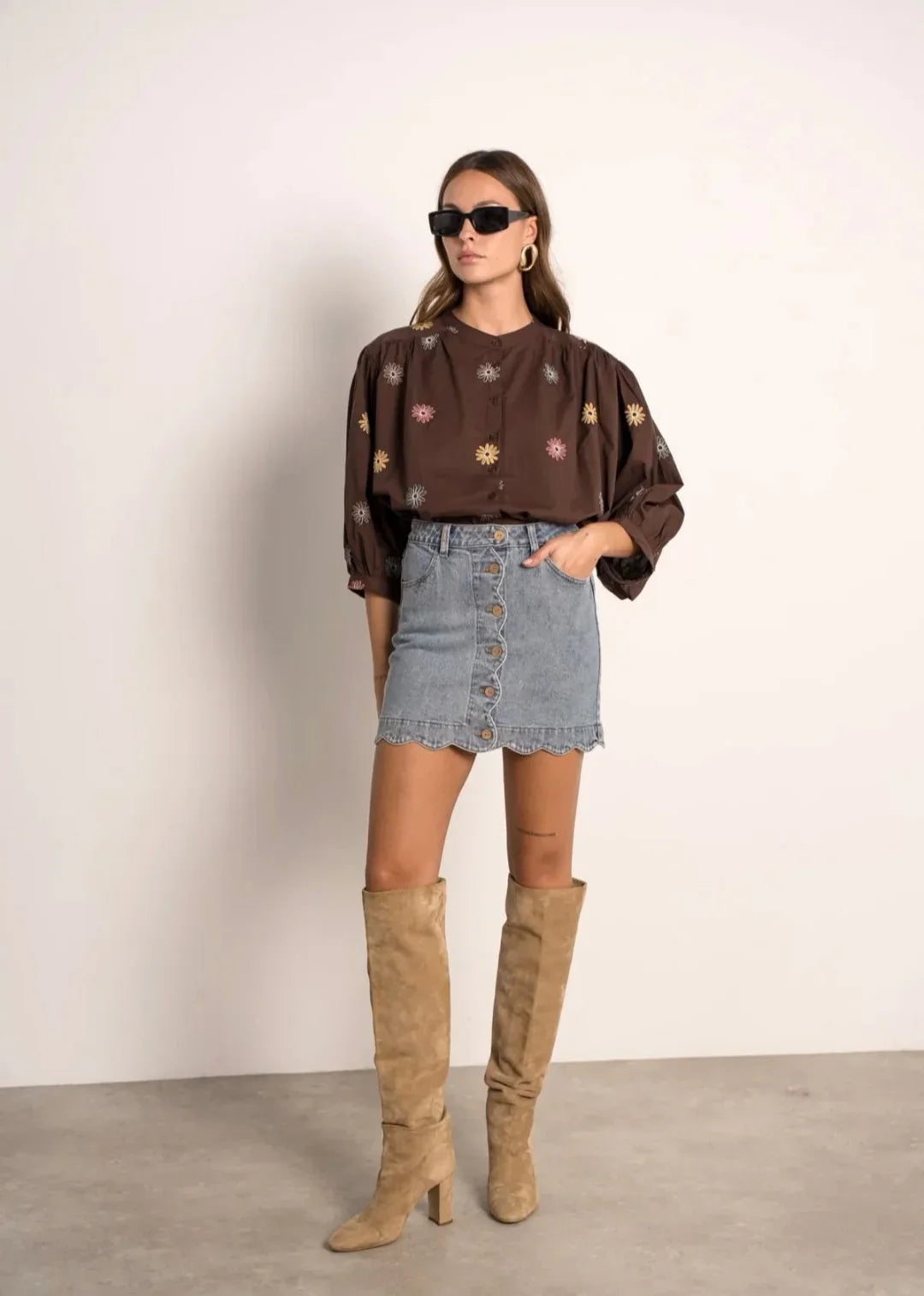 Femme en blouse marron à motifs, jupe en jean, bottes beiges, style prêt-à-porter tendance