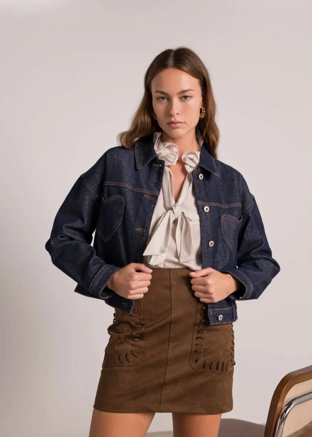 Jeune femme portant une veste en jean, chemisier à nœud et jupe marron, mode tendance femme.