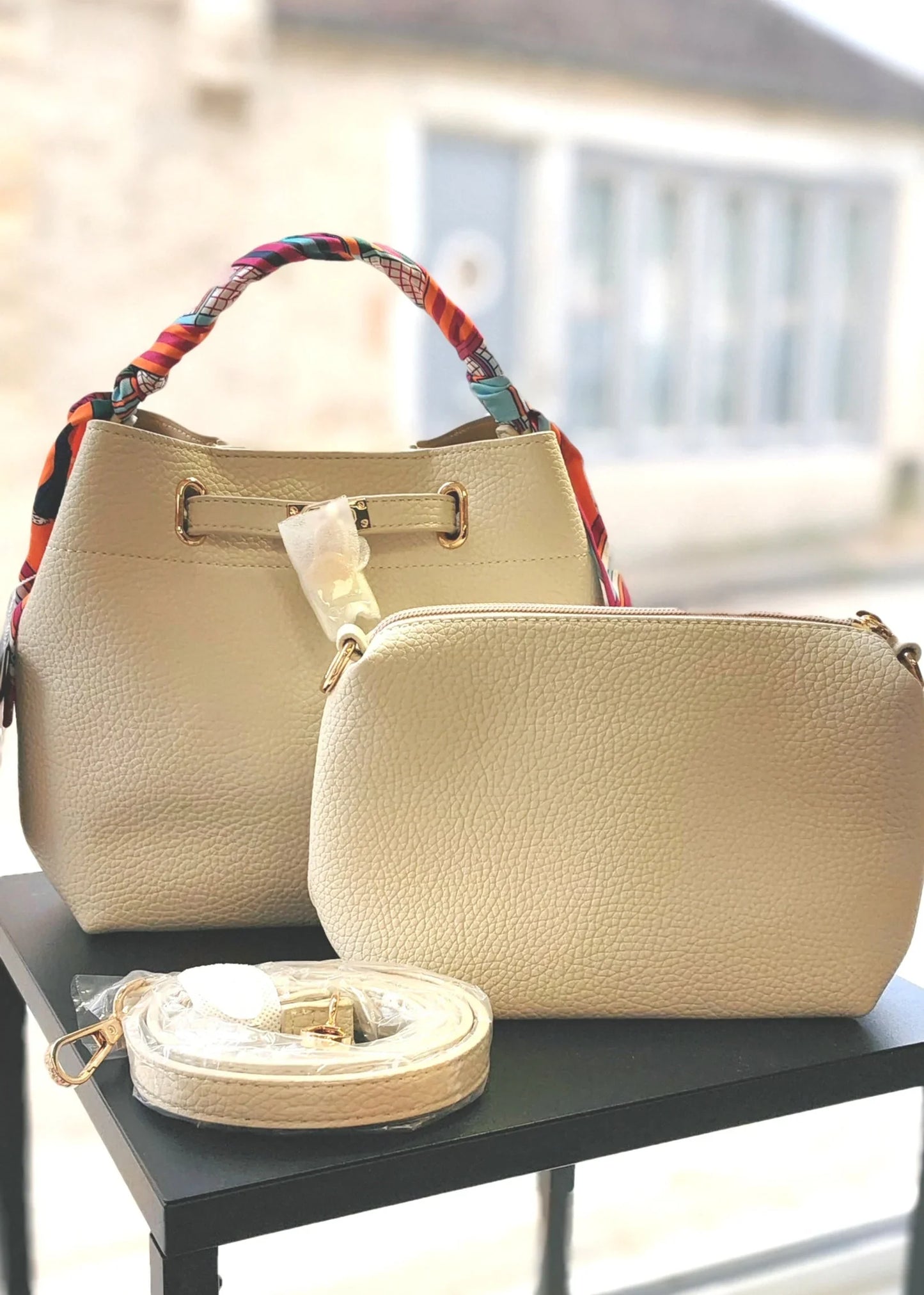 Sac à main beige pour femme avec poignée ruban multicolore, pochette et bandoulière assortie.